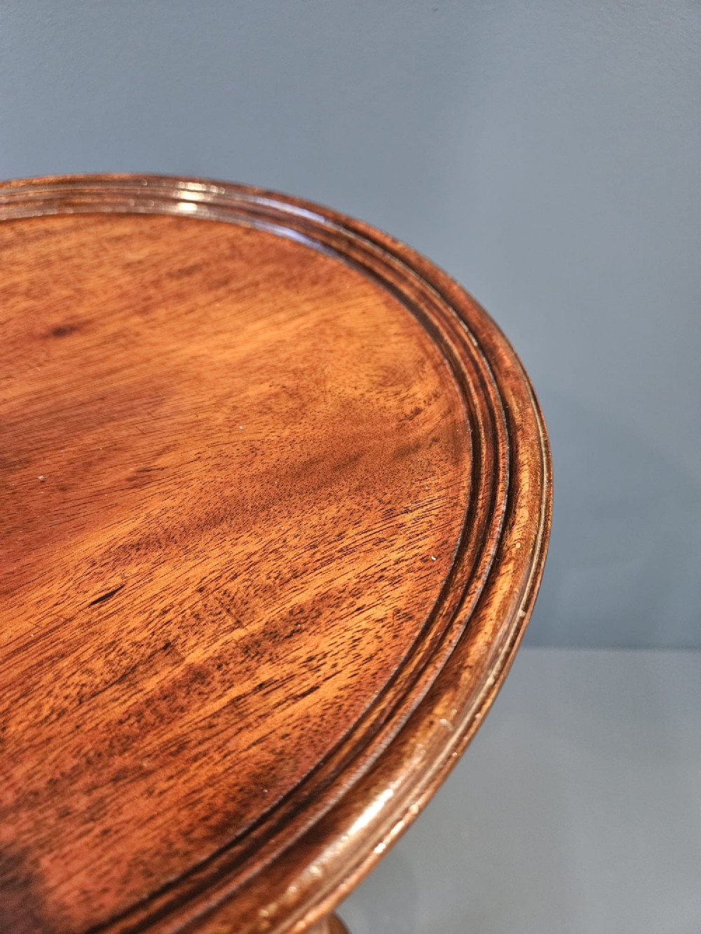 A Georgian mahogany wine table featuring a circular top with a moulded rim supported by a turned pedestal stem on tripod legs. View III