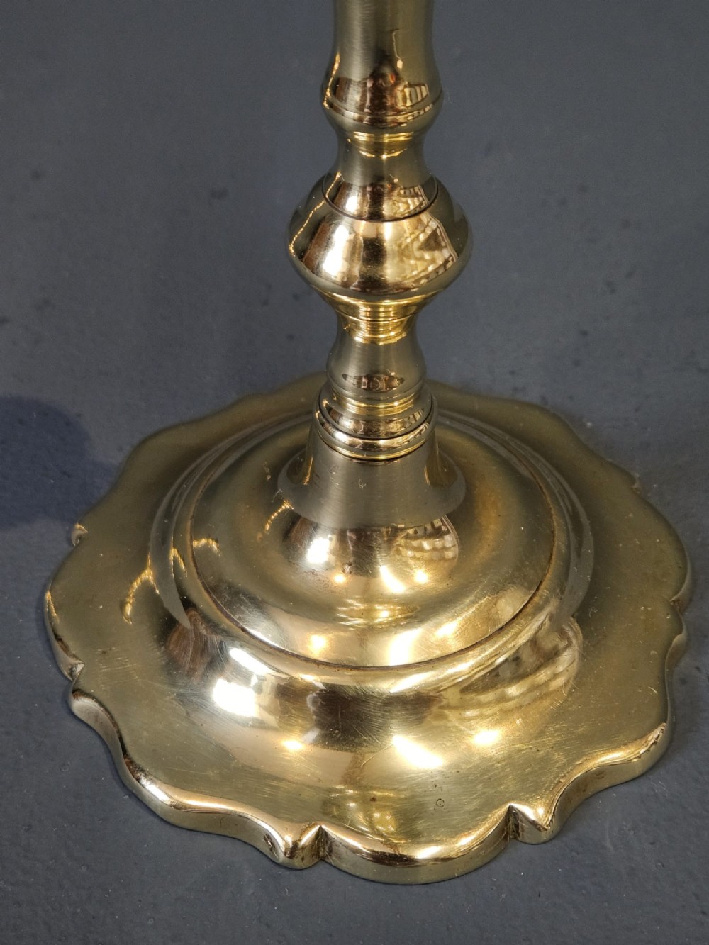 A pair of polished George III brass candlesticks with turned stems and scalloped petal-shaped bases. View III