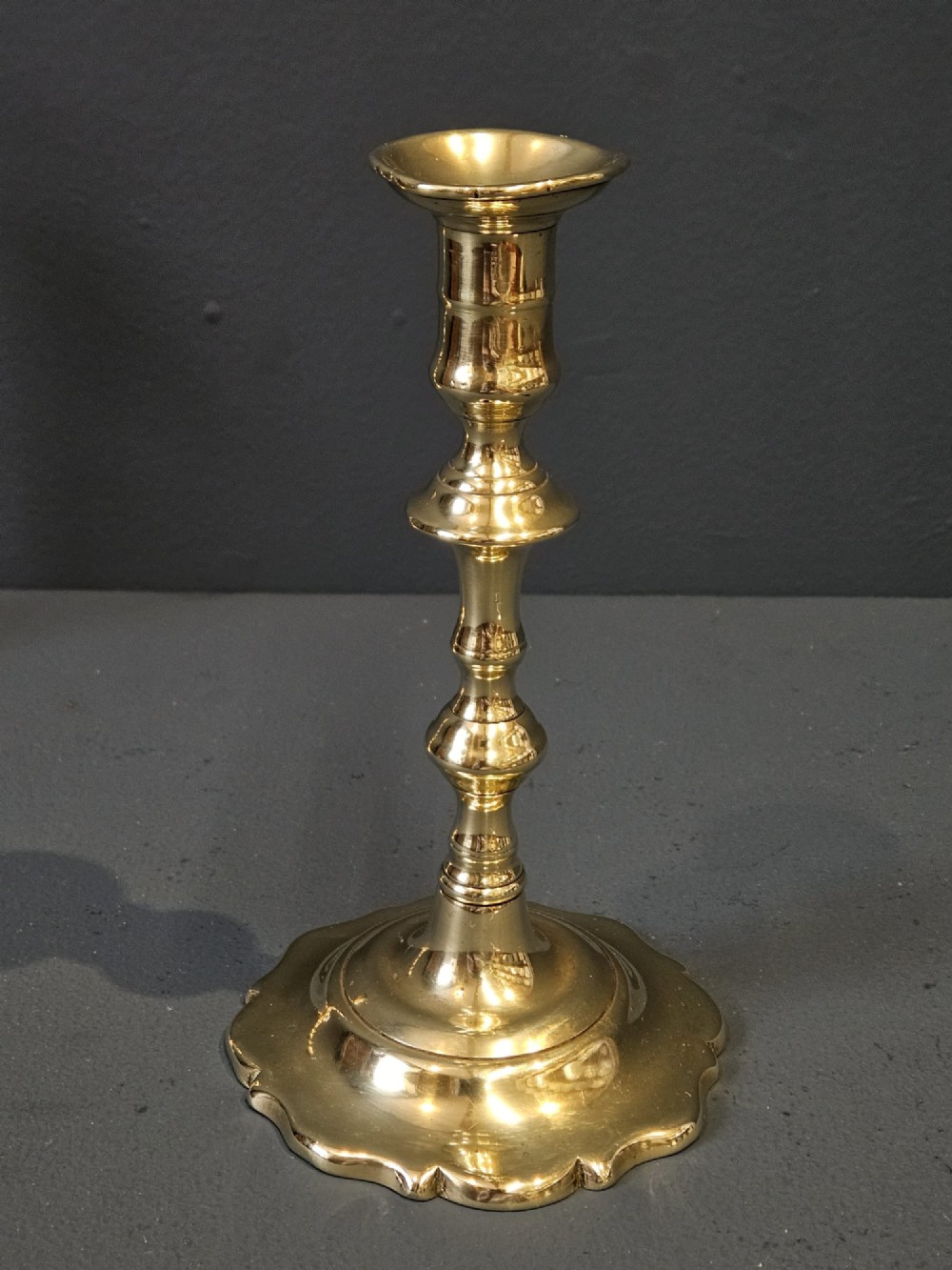 A pair of polished George III brass candlesticks with turned stems and scalloped petal-shaped bases. View IV