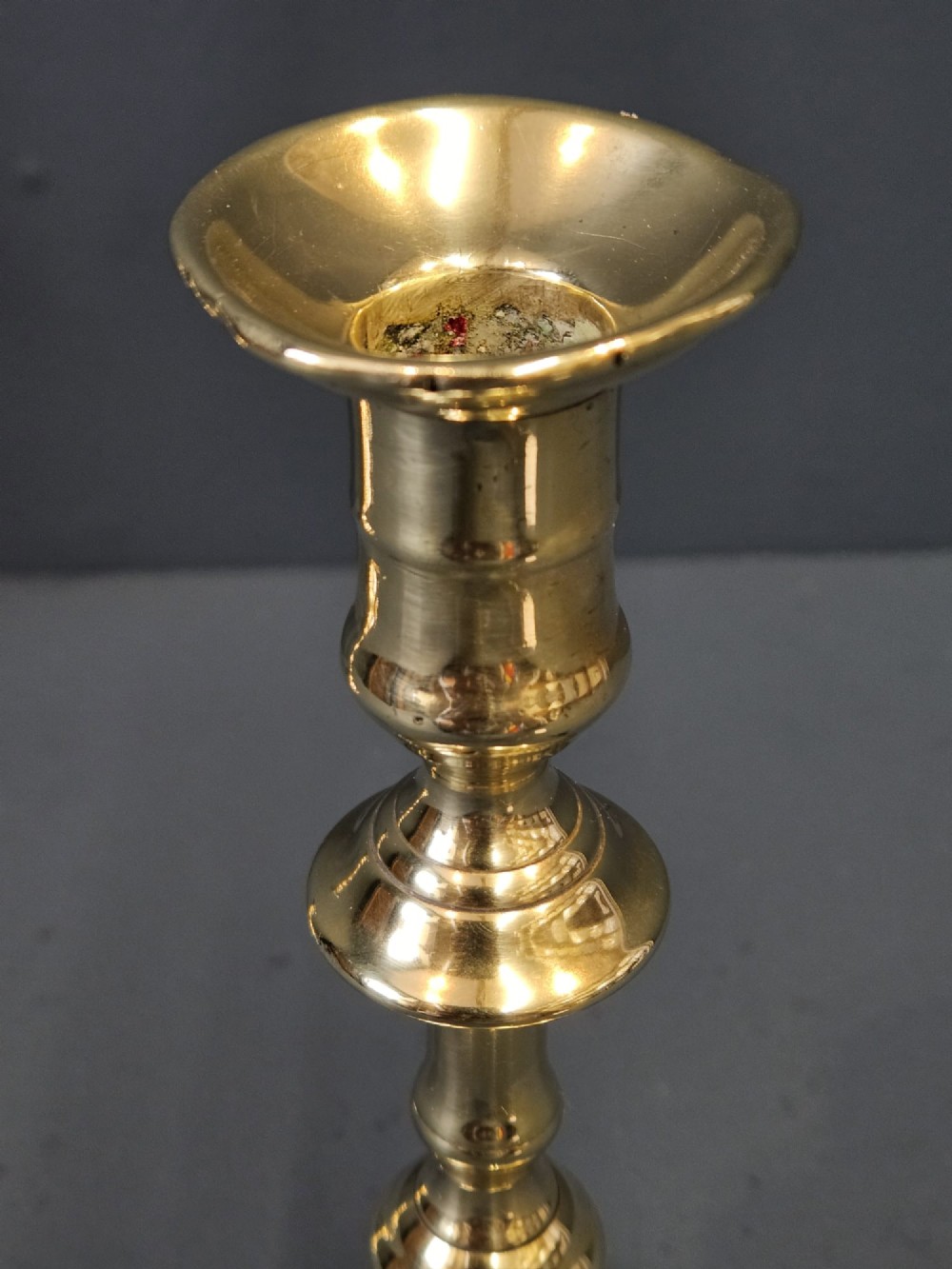 A pair of polished George III brass candlesticks with turned stems and scalloped petal-shaped bases. View V