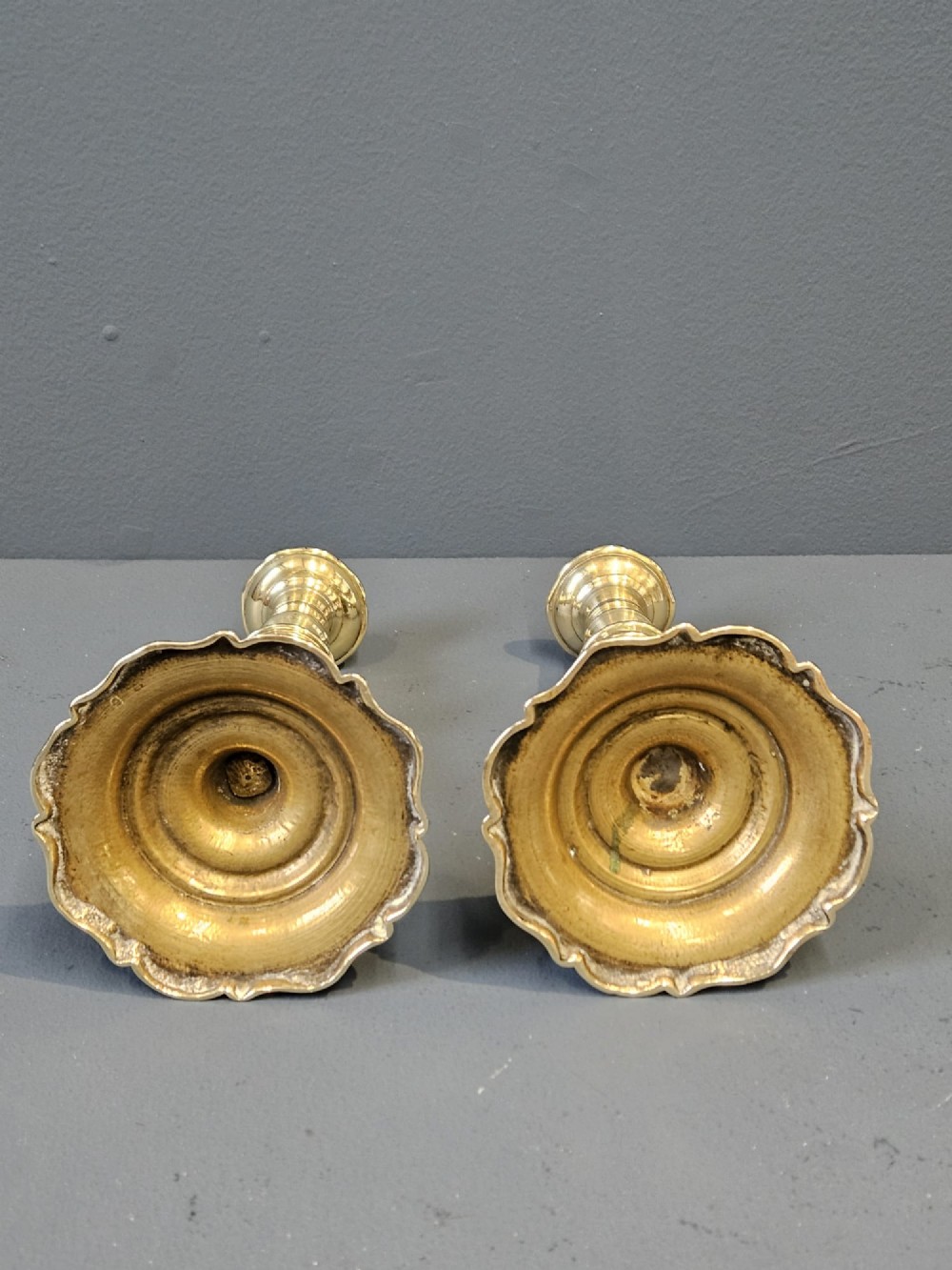 A pair of polished George III brass candlesticks with turned stems and scalloped petal-shaped bases. View VI