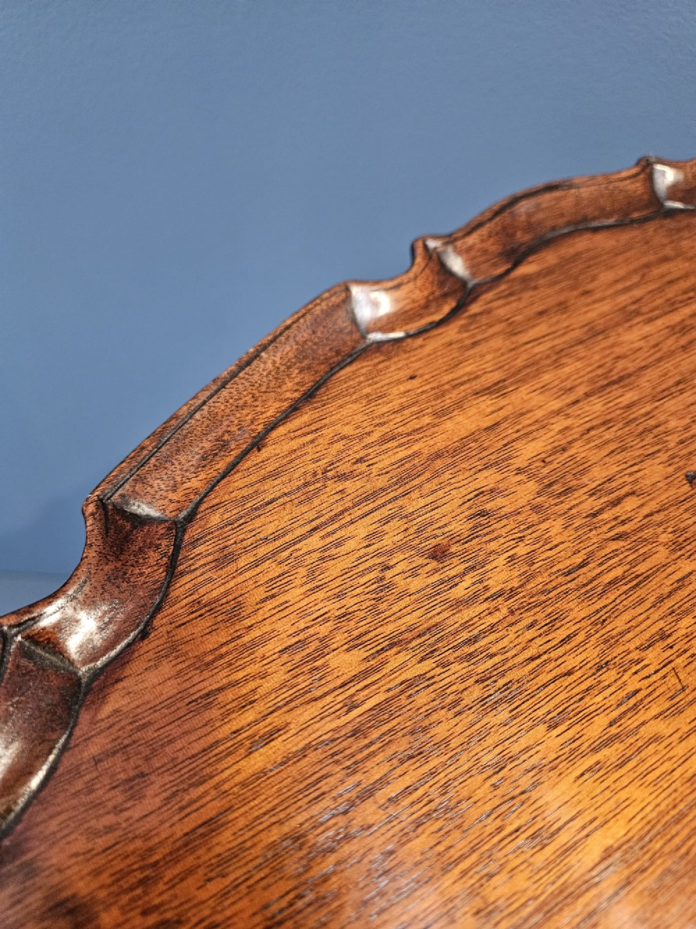 An Edwardian mahogany occasional table featuring an oval top with a raised piecrust edge, supported by a carved central pedestal and tripod cabriole legs. View VIII