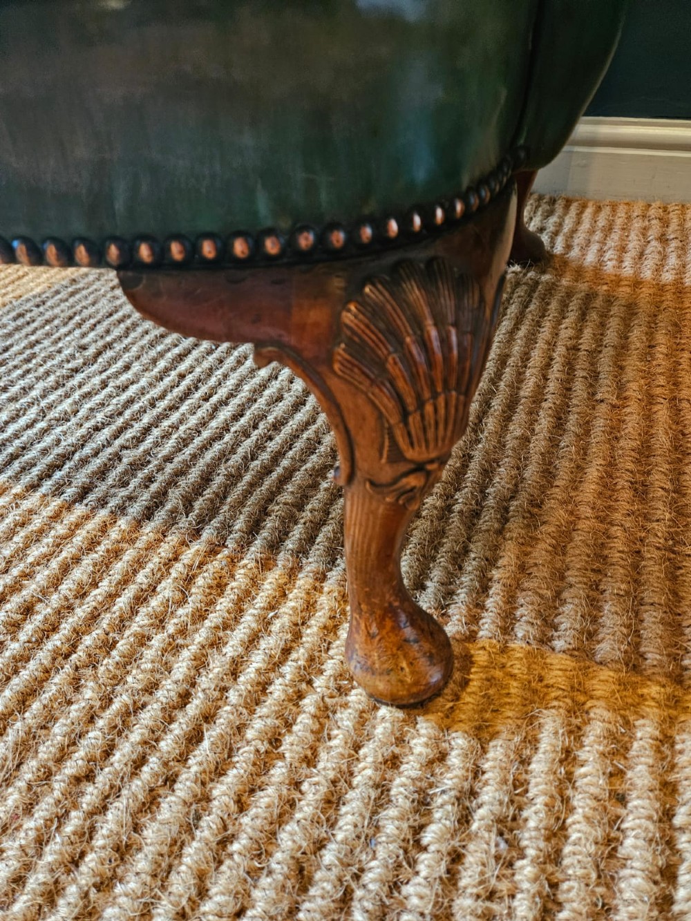 A George III wingback armchair in green leather upholstery featuring brass studding and carved walnut cabriole front legs. View IV