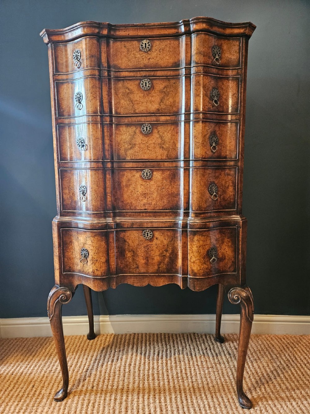 An Edwardian burr walnut chest on stand featuring a serpentine front, ornate brass handles, and slender cabriole legs. View V