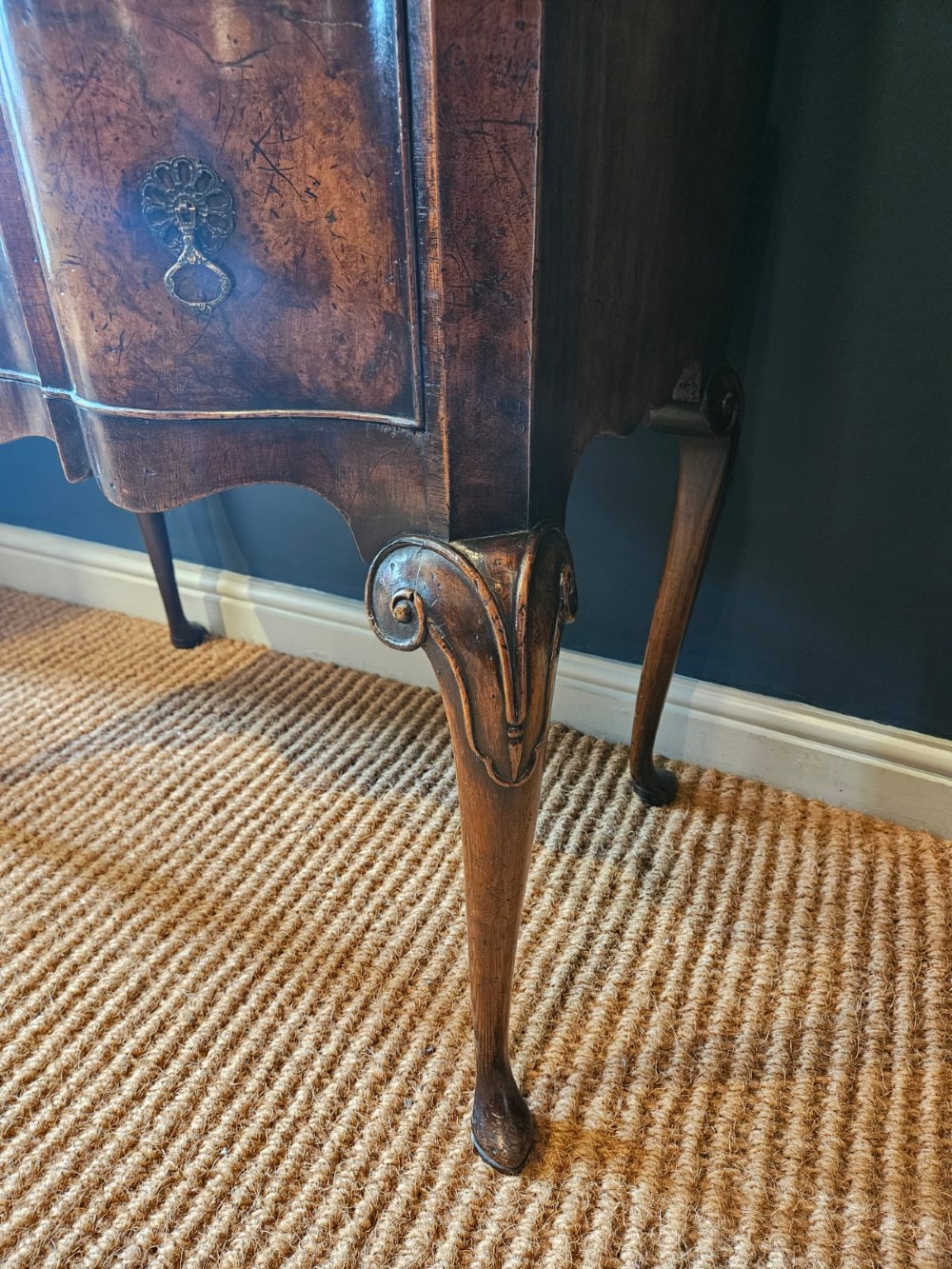 An Edwardian burr walnut chest on stand featuring a serpentine front, ornate brass handles, and slender cabriole legs. View VI