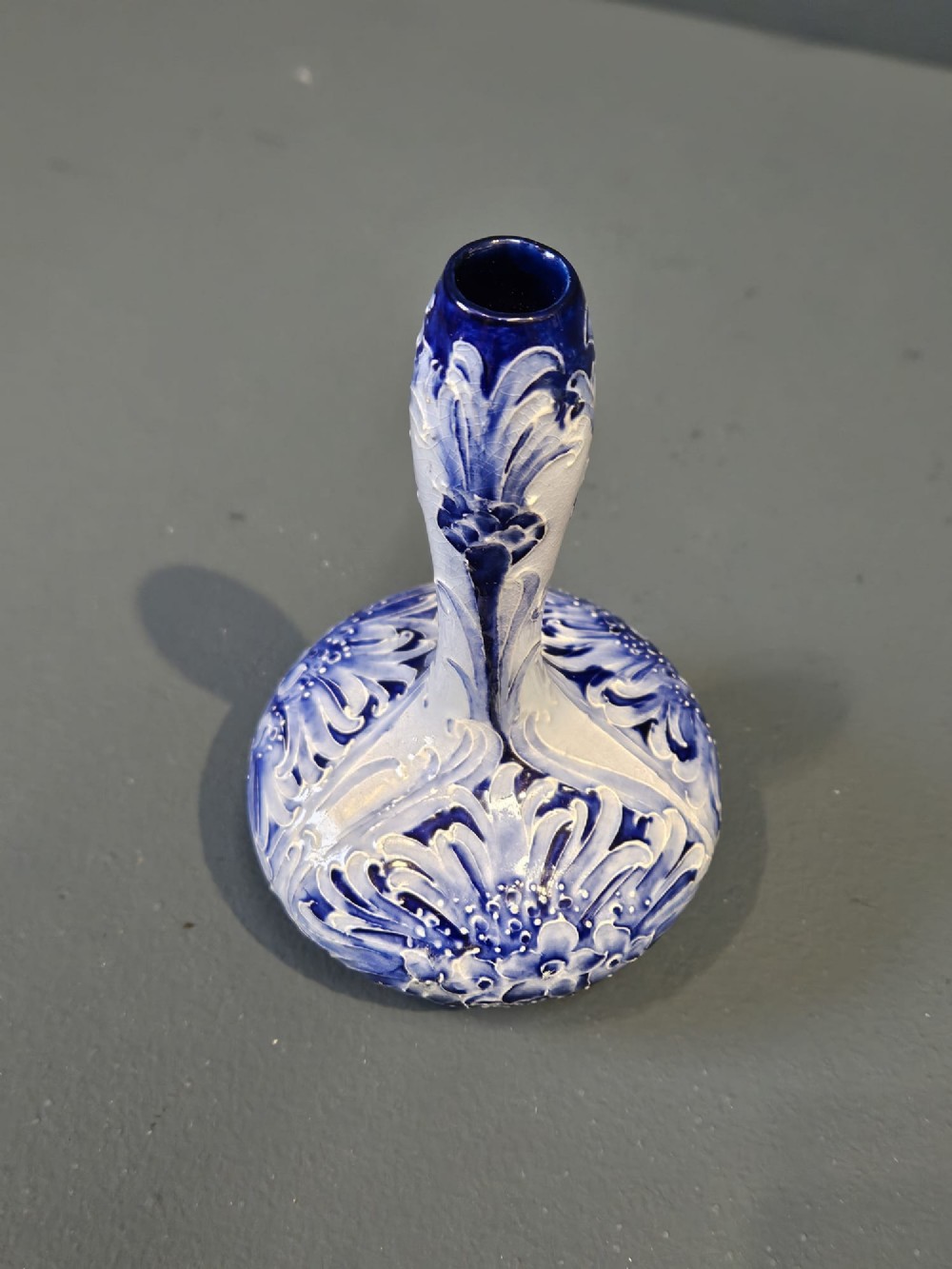 An Art Nouveau ceramic vase featuring a bulbous base, slender elongated neck, and cobalt blue tube-lined cornflower motif on a pale ground. View III