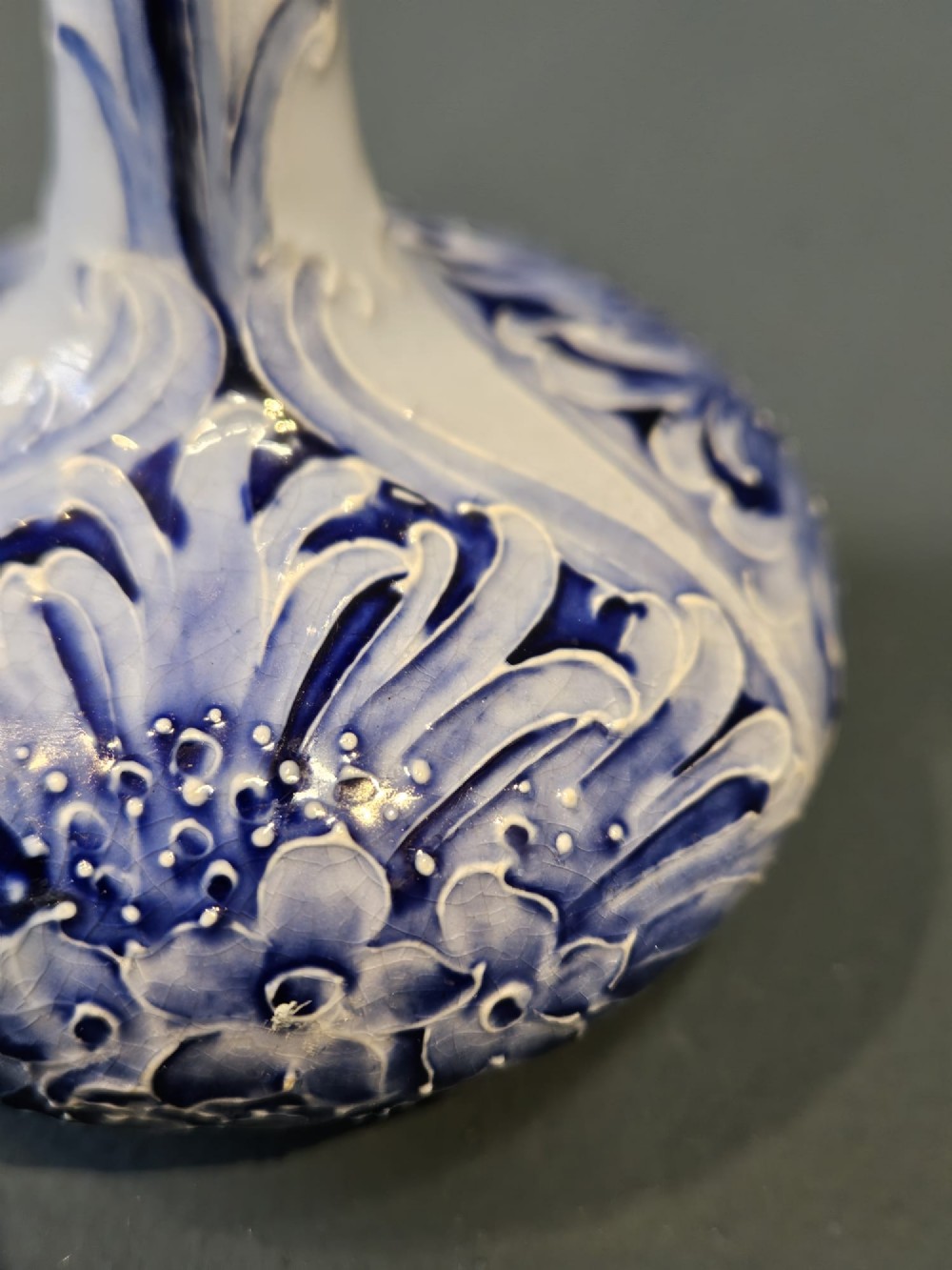 An Art Nouveau ceramic vase featuring a bulbous base, slender elongated neck, and cobalt blue tube-lined cornflower motif on a pale ground. View VI