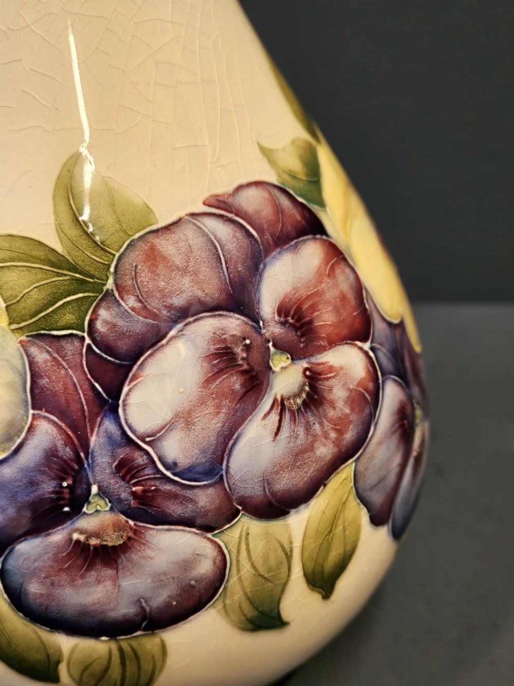An Art Nouveau Macintyre Moorcroft earthenware vase featuring hand-painted tubelined pansy motifs on a cream ground with a green flared rim. View III