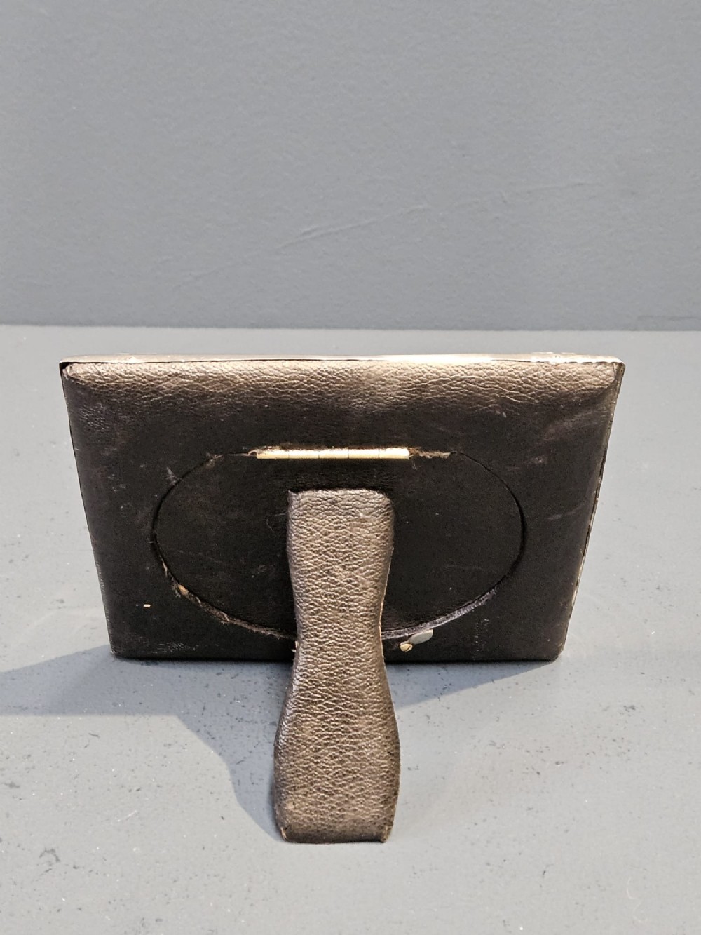 An Edwardian sterling silver square photo frame featuring an oval aperture, embossed cherub heads at each corner, and scrollwork detailing. View IV