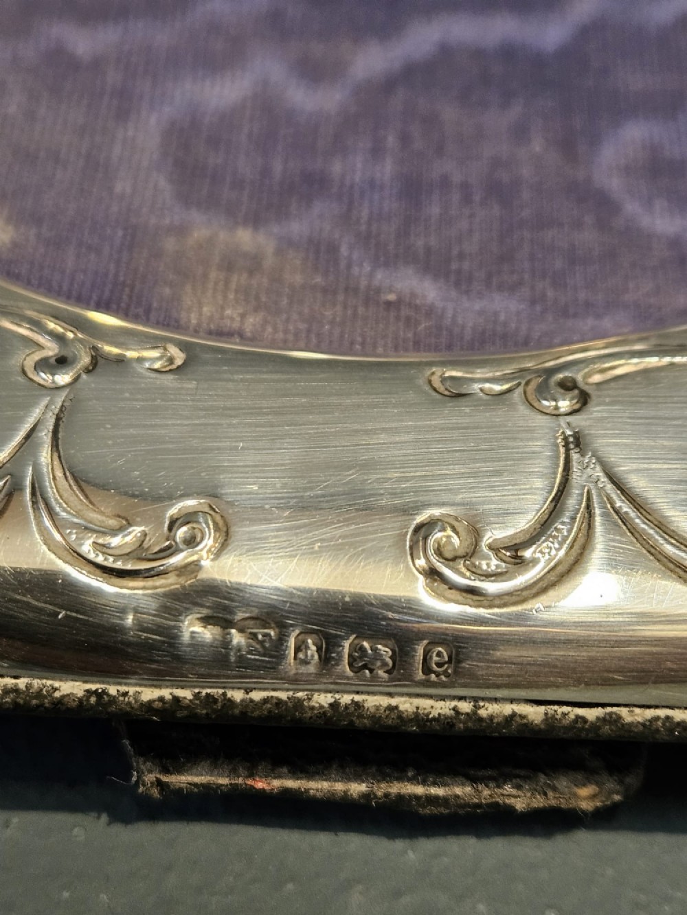 An Edwardian sterling silver square photo frame featuring an oval aperture, embossed cherub heads at each corner, and scrollwork detailing. View V