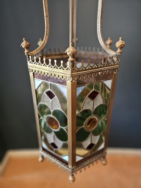 A vertical hexagonal brass hanging lantern featuring stained leaded glass panels with green, purple, and amber floral motifs. View III