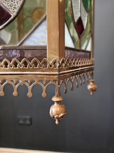 A vertical hexagonal brass hanging lantern featuring stained leaded glass panels with green, purple, and amber floral motifs. View VI