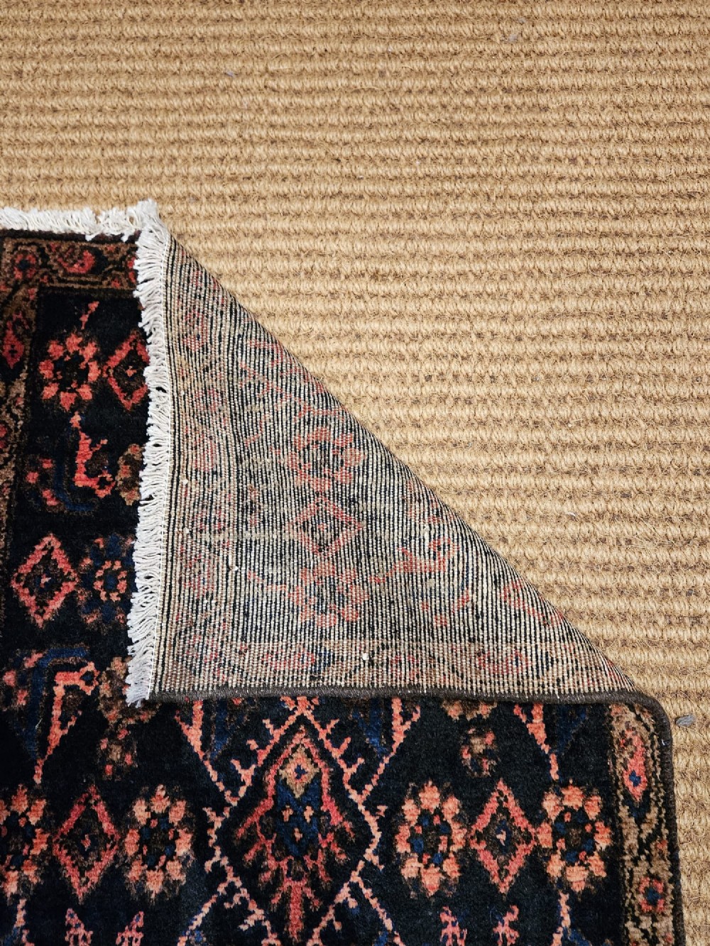 A long hand-knotted wool runner rug featuring repeating geometric diamond patterns in red, cream, and terracotta on a dark navy background with fringe edges. View VIII