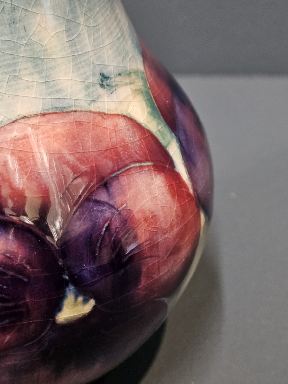 A Moorcroft earthenware vase featuring a bulbous body and flared neck decorated with hand-painted tubelined purple and wine-red pansies beneath a pale blue glaze. View III