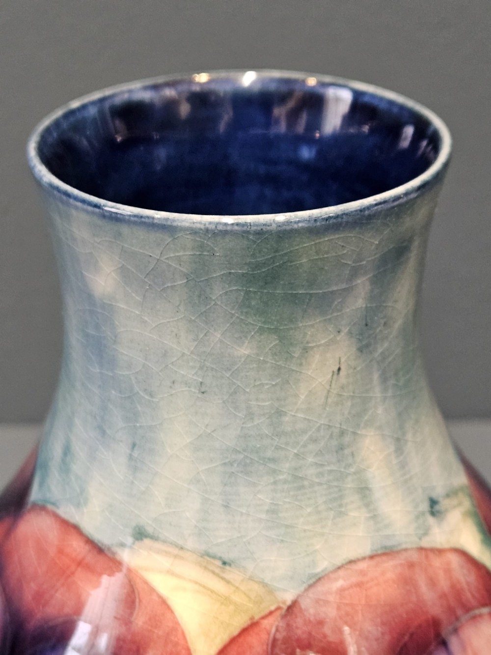 A Moorcroft earthenware vase featuring a bulbous body and flared neck decorated with hand-painted tubelined purple and wine-red pansies beneath a pale blue glaze. View IV