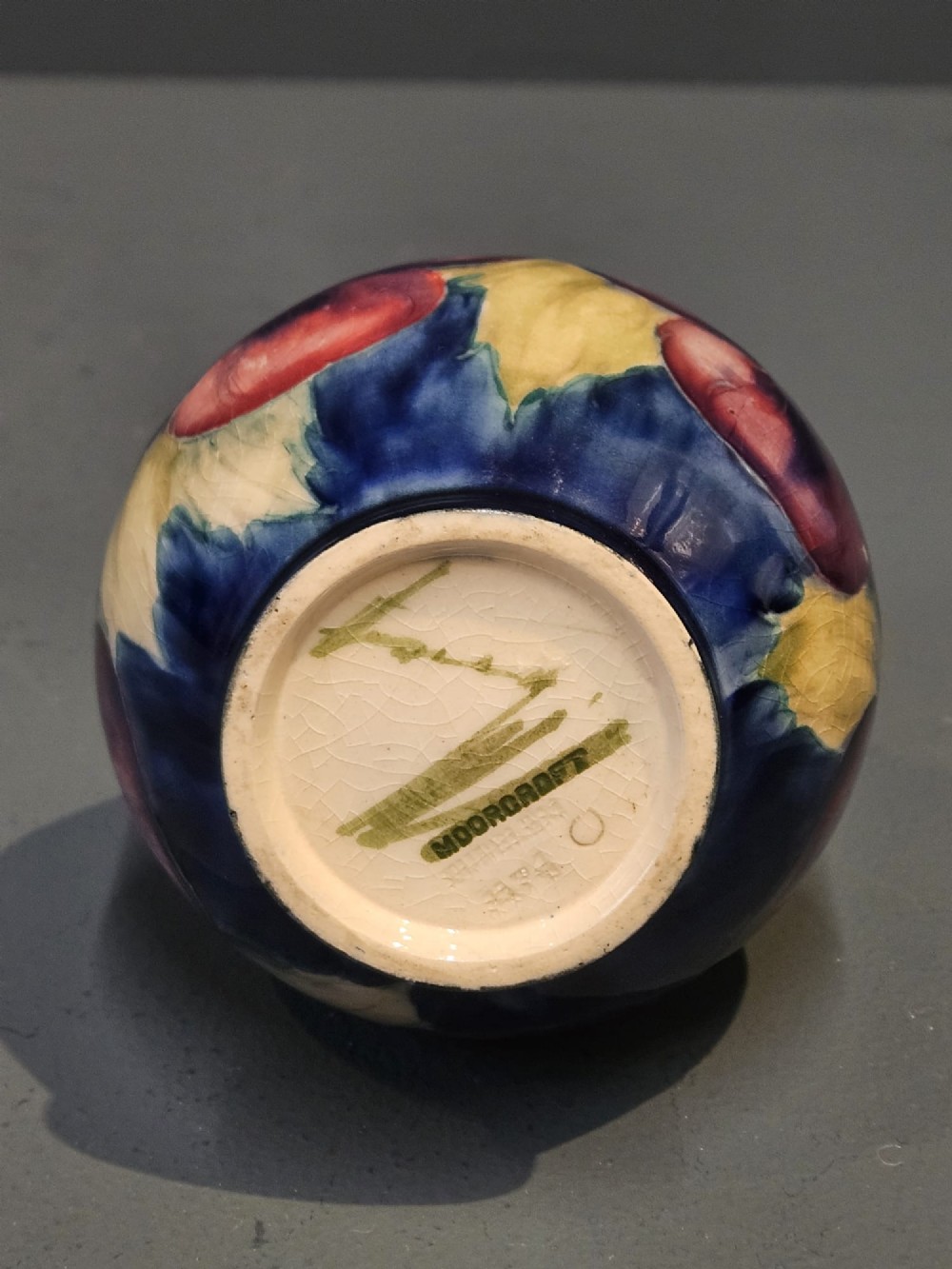 A Moorcroft earthenware vase featuring a bulbous body and flared neck decorated with hand-painted tubelined purple and wine-red pansies beneath a pale blue glaze. View VI