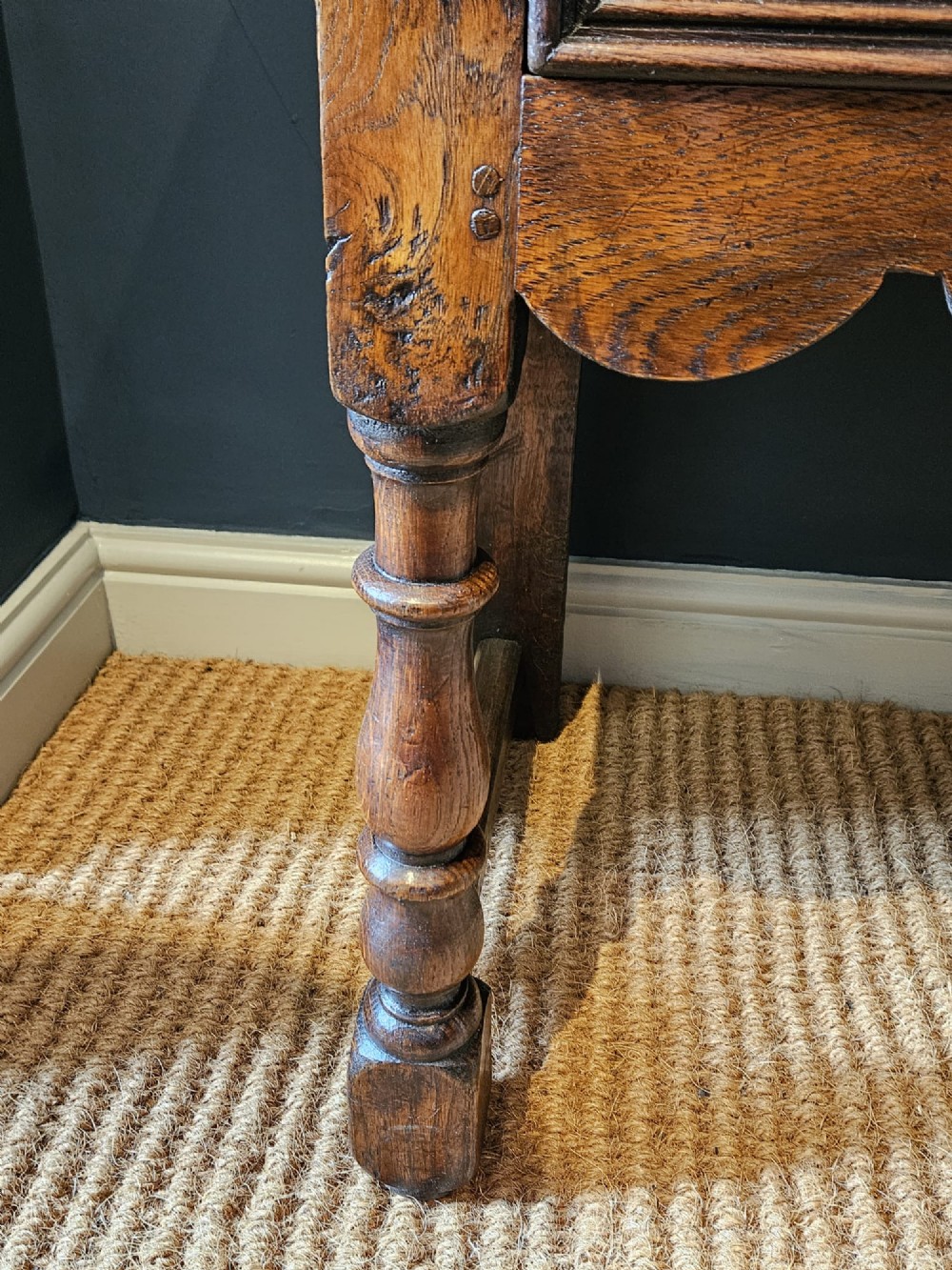 An early 18th-century George I oak dresser featuring three drawers with geometric mitred mouldings, brass drop handles, a scalloped apron, and turned legs. View VI