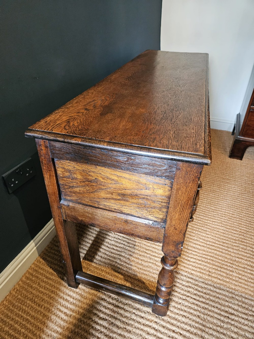An early 18th-century George I oak dresser featuring three drawers with geometric mitred mouldings, brass drop handles, a scalloped apron, and turned legs. View VII