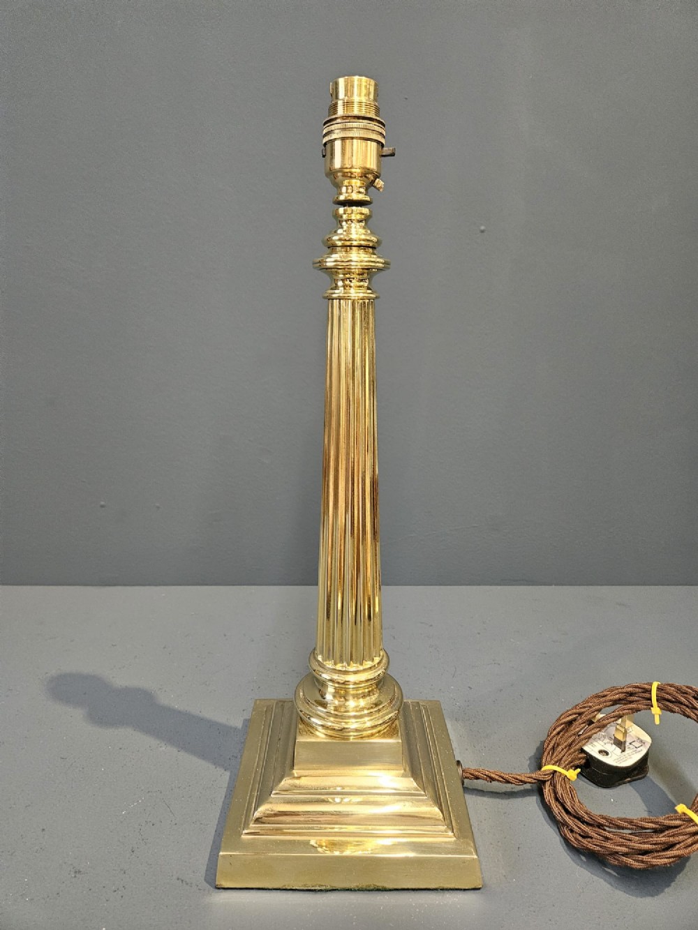 A late Victorian brass table lamp featuring a tapered reeded column stem set upon a stepped square base. View II