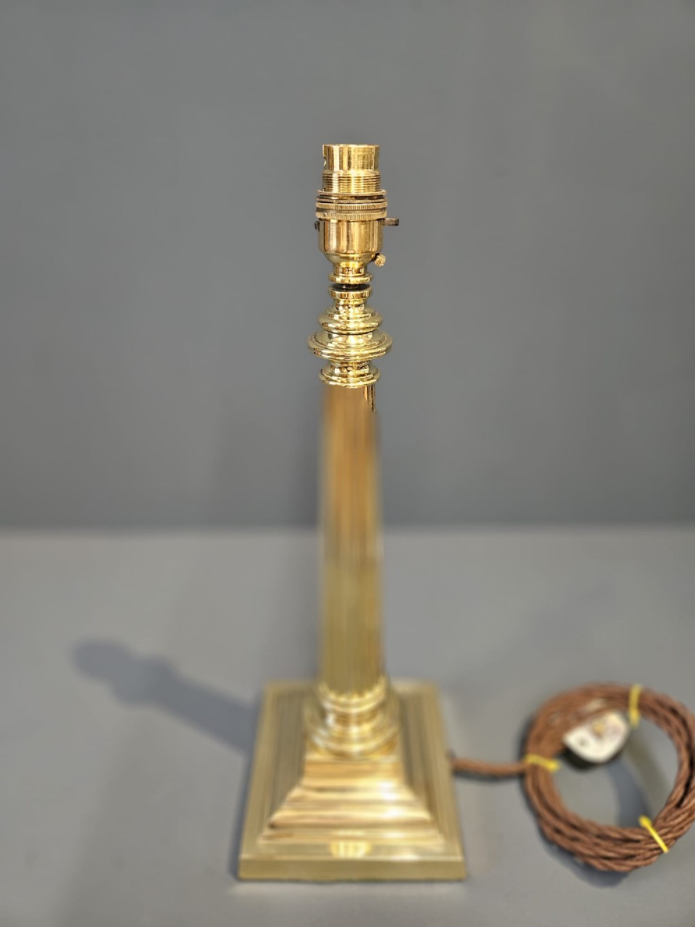 A late Victorian brass table lamp featuring a tapered reeded column stem set upon a stepped square base. View V