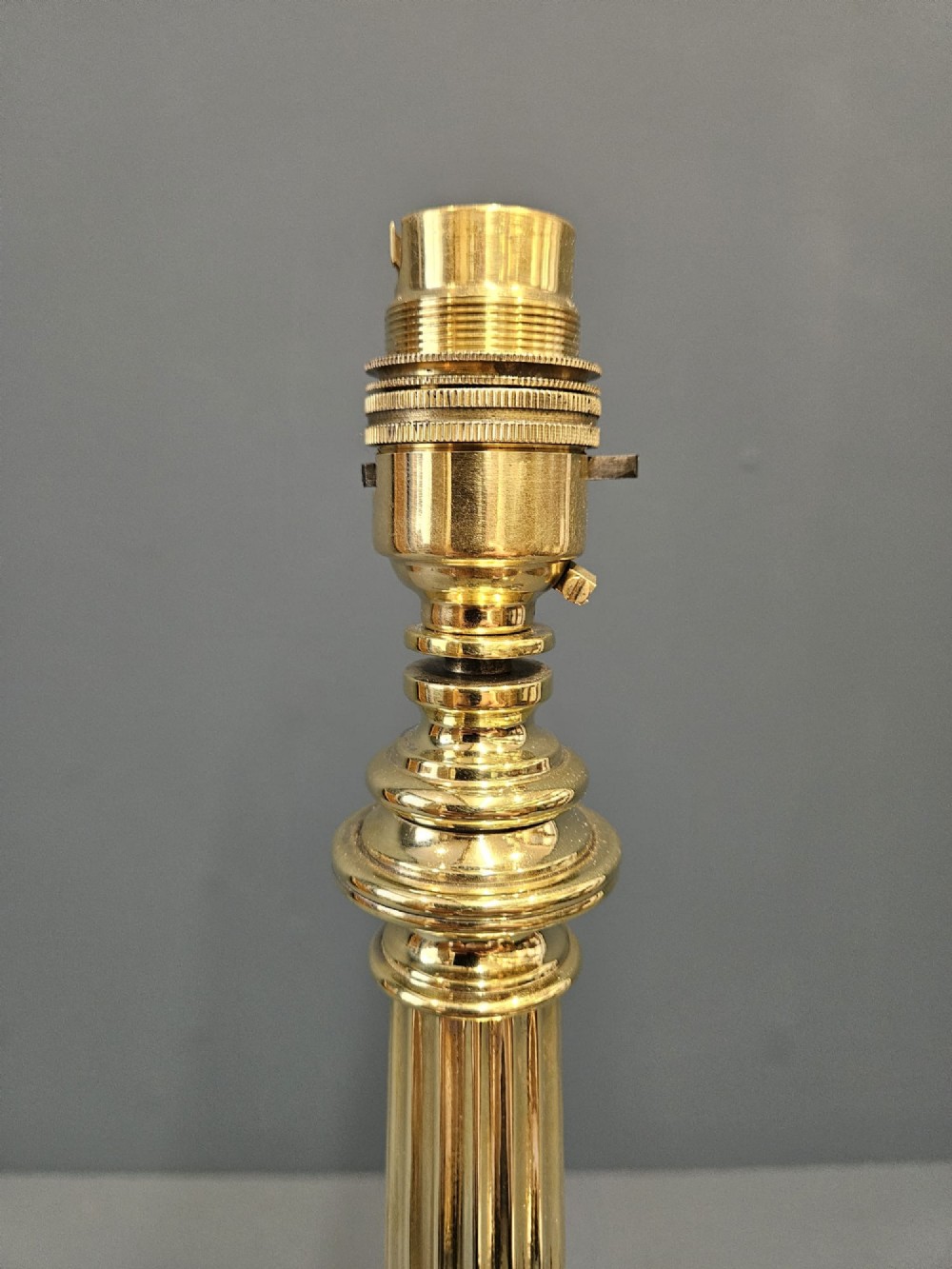 A late Victorian brass table lamp featuring a tapered reeded column stem set upon a stepped square base. View VI