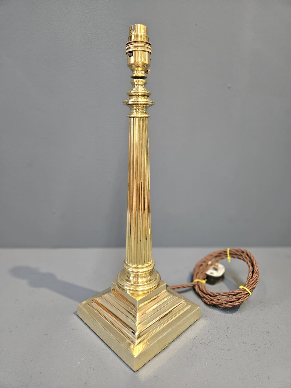 A late Victorian brass table lamp featuring a tapered reeded column stem set upon a stepped square base. View VII