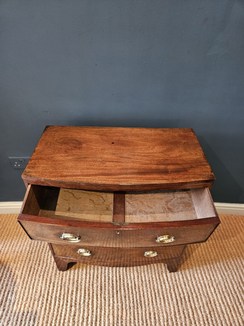 An early Victorian mahogany bow-fronted chest featuring three full-length drawers with oval brass handles and a curved lower apron. View III