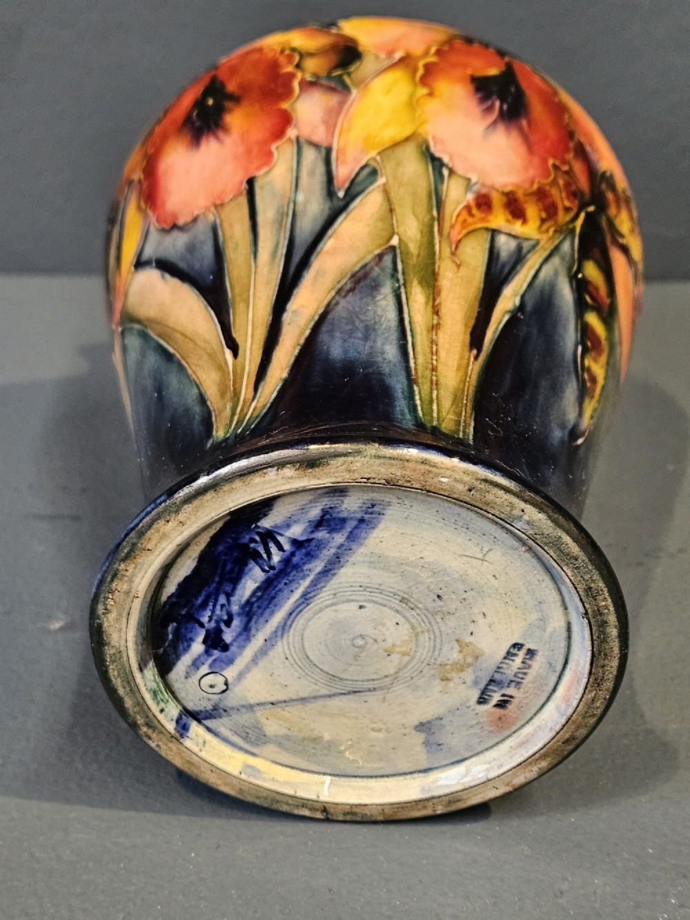 A glazed earthenware vase featuring tube-lined yellow and purple orchid motifs set against a rich blue and green flambe background. View IV