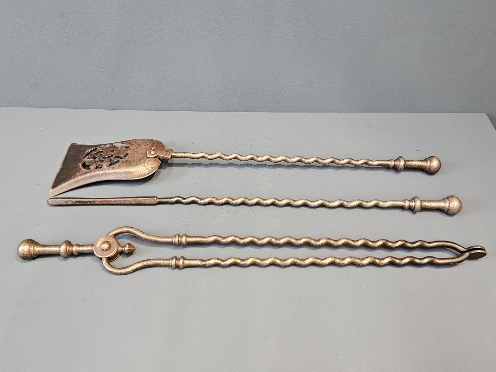 A set of three Georgian steel fire irons featuring barley twist shafts, turned urn finials, and a pierced decorative shovel blade. View IV
