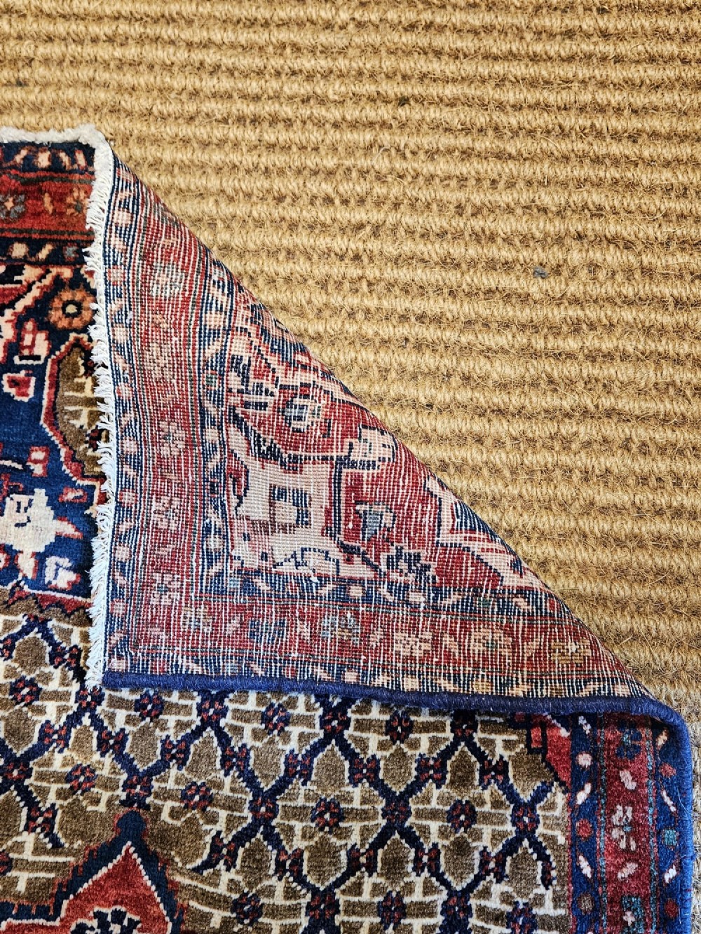 A small rectangular hand-knotted wool rug featuring a central star medallion, geometric lattice field, and deep red and blue borders. View V