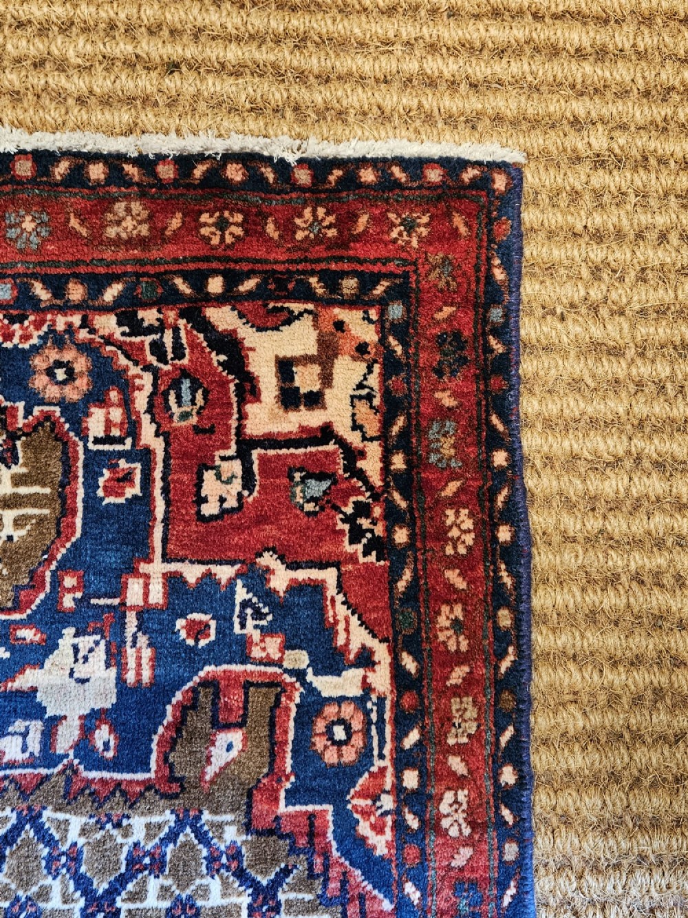 A small rectangular hand-knotted wool rug featuring a central star medallion, geometric lattice field, and deep red and blue borders. View VI