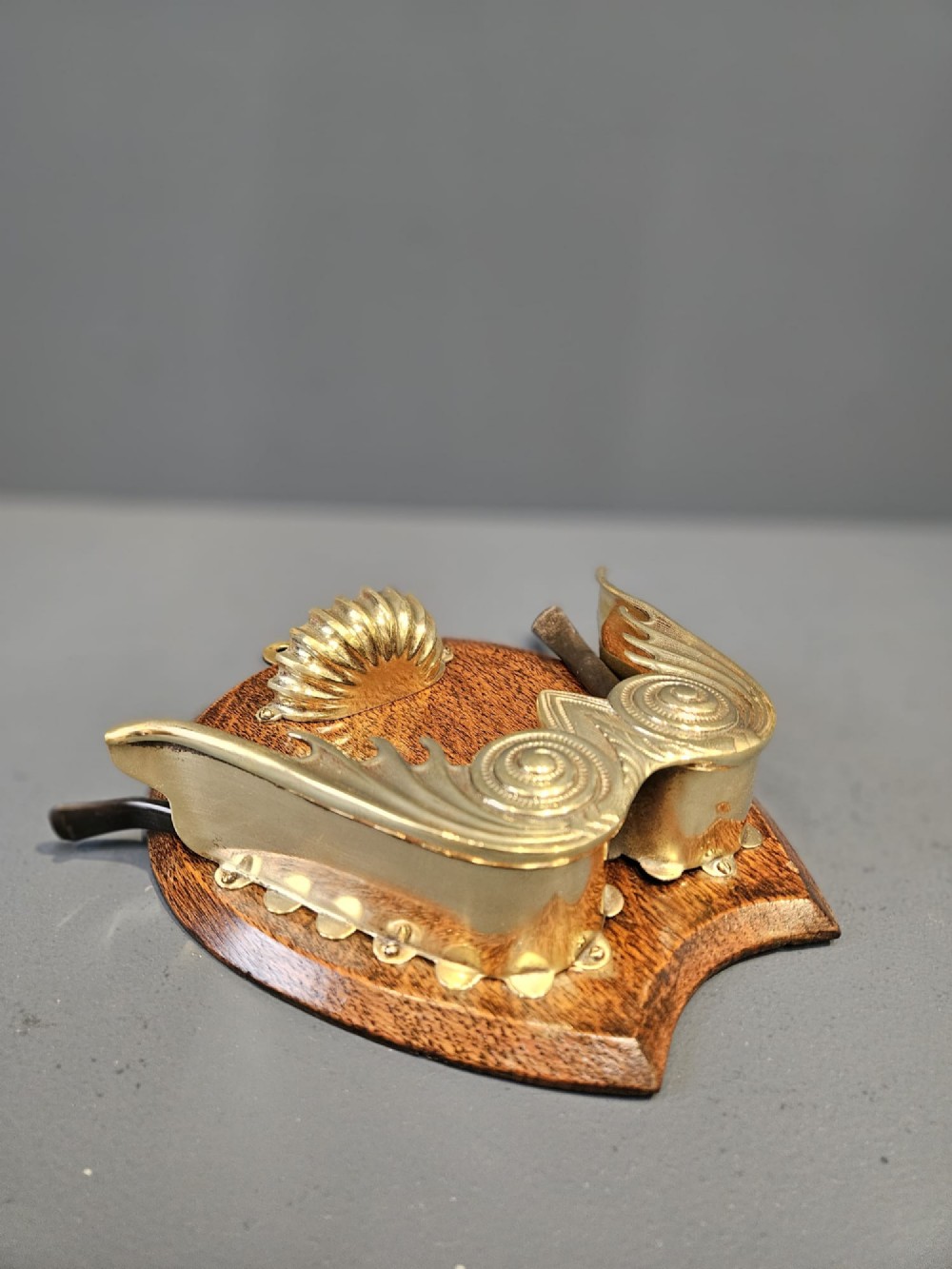 A Victorian wall-mounted oak pipe rack featuring ornamental cast brass scrollwork holders and a brass shell motif. View III