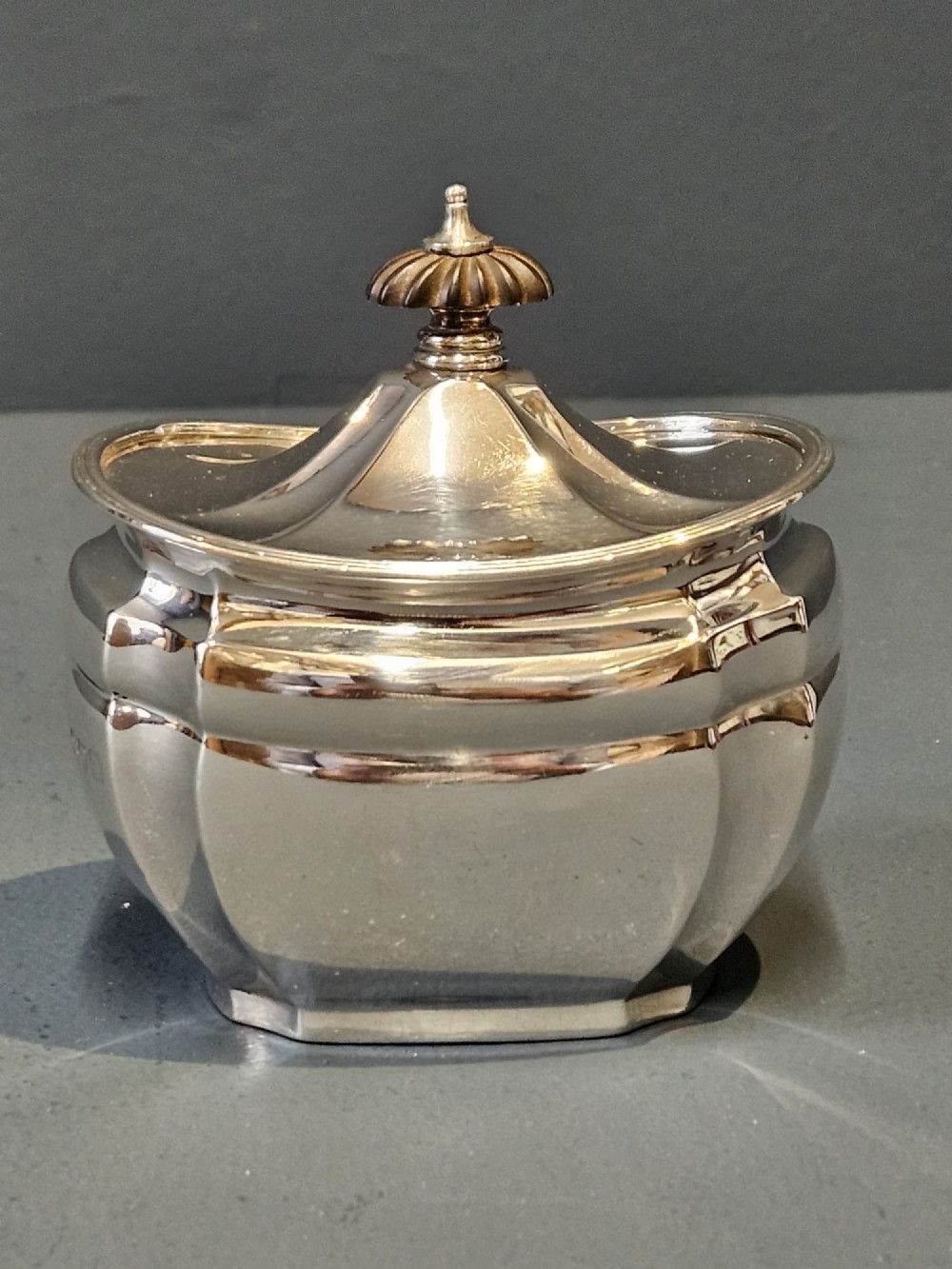 A shaped Victorian silver tea caddy featuring a lobed body, a stepped cover, and a gadrooned finial.
