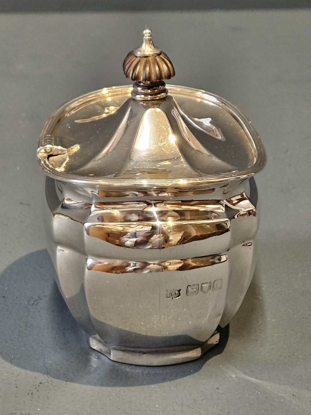 A shaped Victorian silver tea caddy featuring a lobed body, a stepped cover, and a gadrooned finial. View V