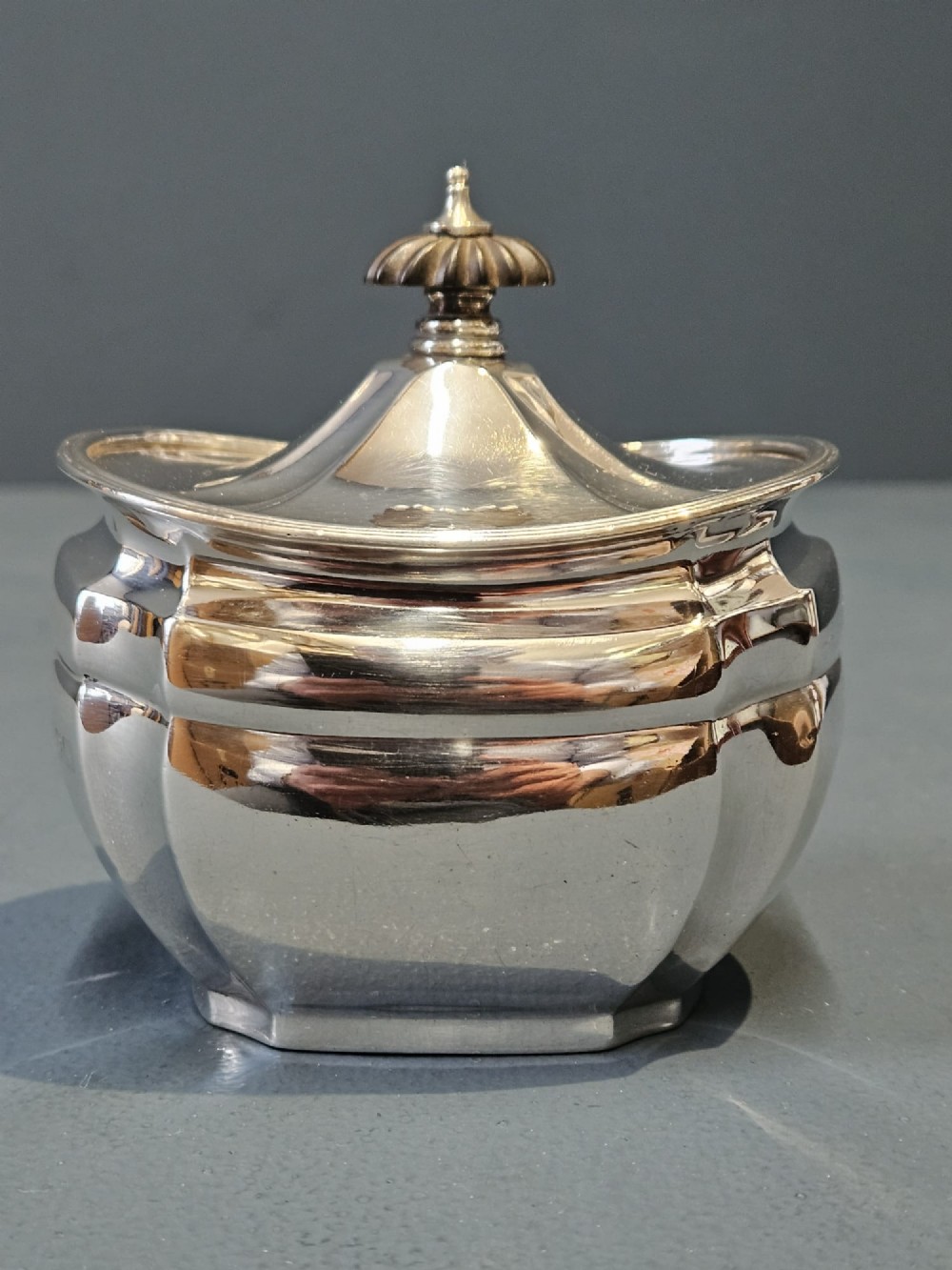 A shaped Victorian silver tea caddy featuring a lobed body, a stepped cover, and a gadrooned finial. View VII