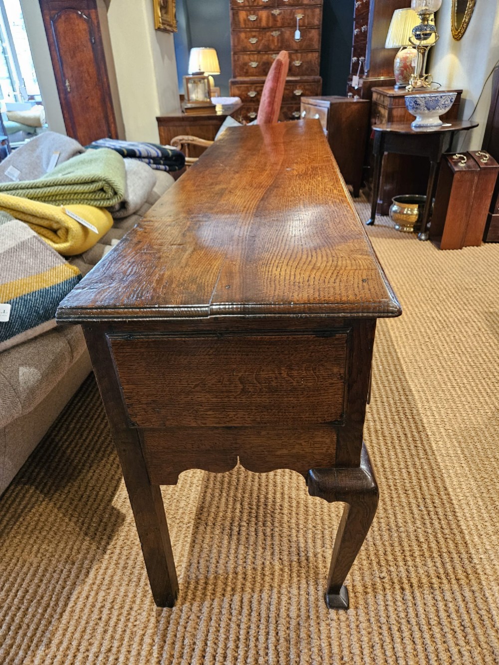 A George II oak dresser base featuring three drawers, brass handles, a shaped apron, and four cabriole legs. View X