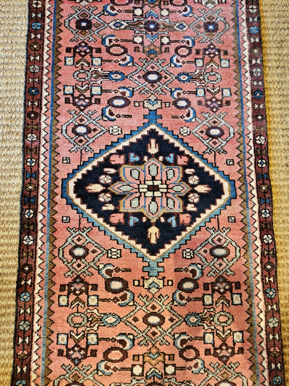 A long hand-knotted pure wool runner rug featuring geometric medallions in rose pink, navy blue, and cream. View III