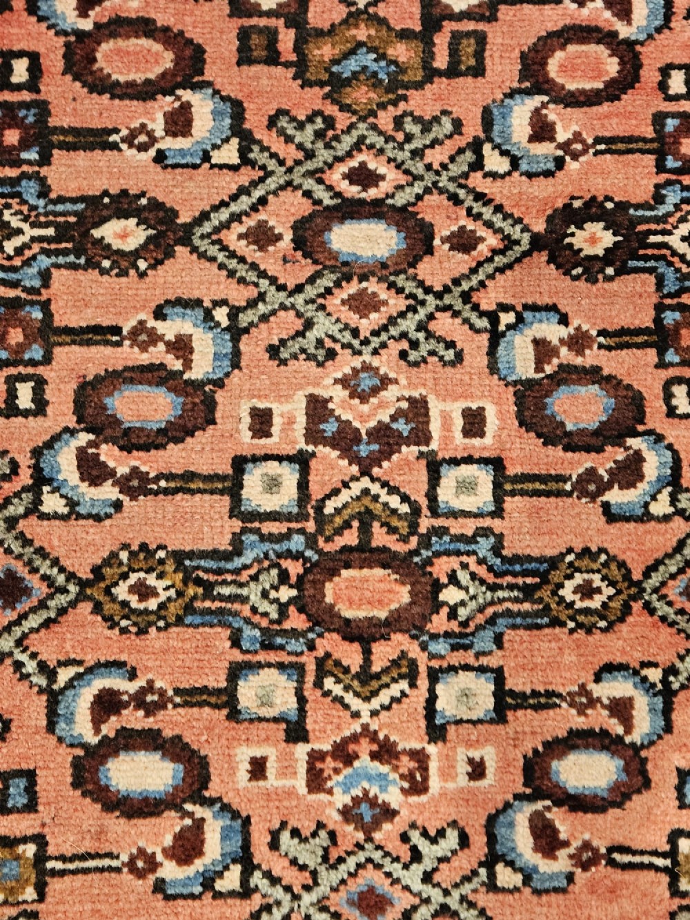A long hand-knotted pure wool runner rug featuring geometric medallions in rose pink, navy blue, and cream. View V