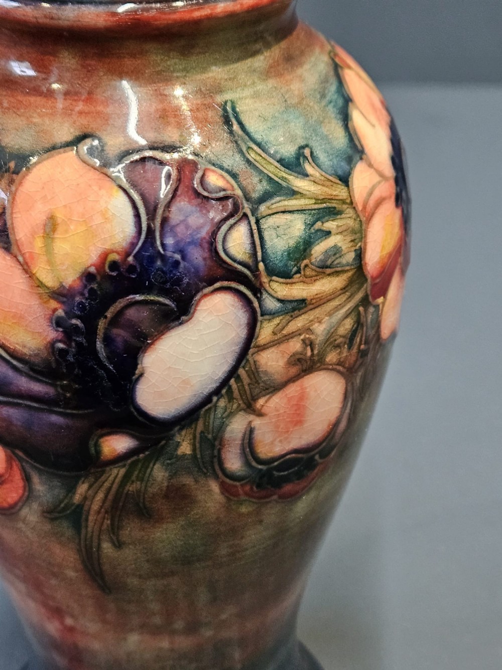 A baluster-shaped ceramic vase featuring hand-painted tubelined anemone flowers over a rich red flambe glaze background. View IV