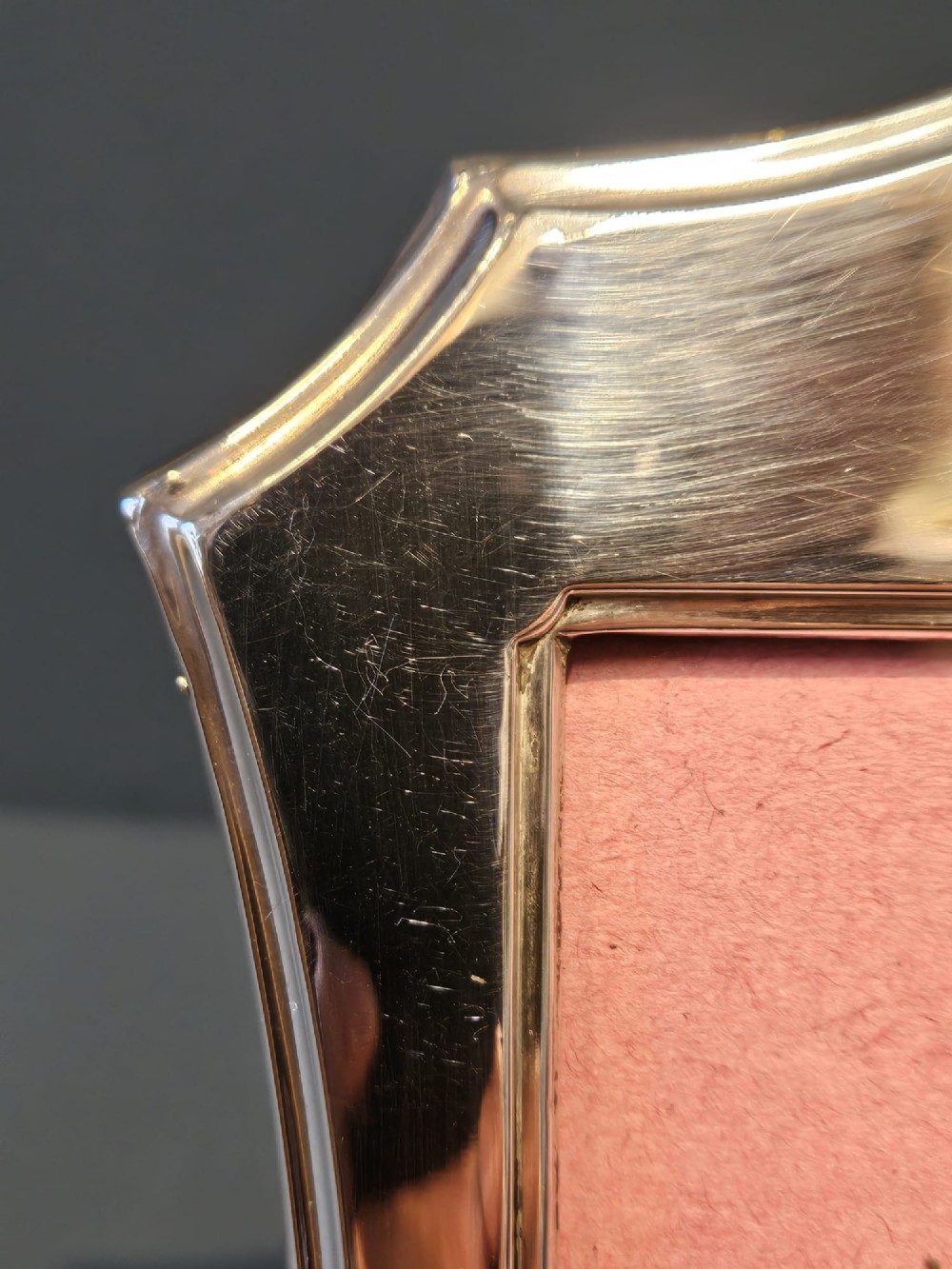 An Edwardian sterling silver photo frame featuring swept concave sides, a shaped crest, polished silver surface, and portrait orientation. View II