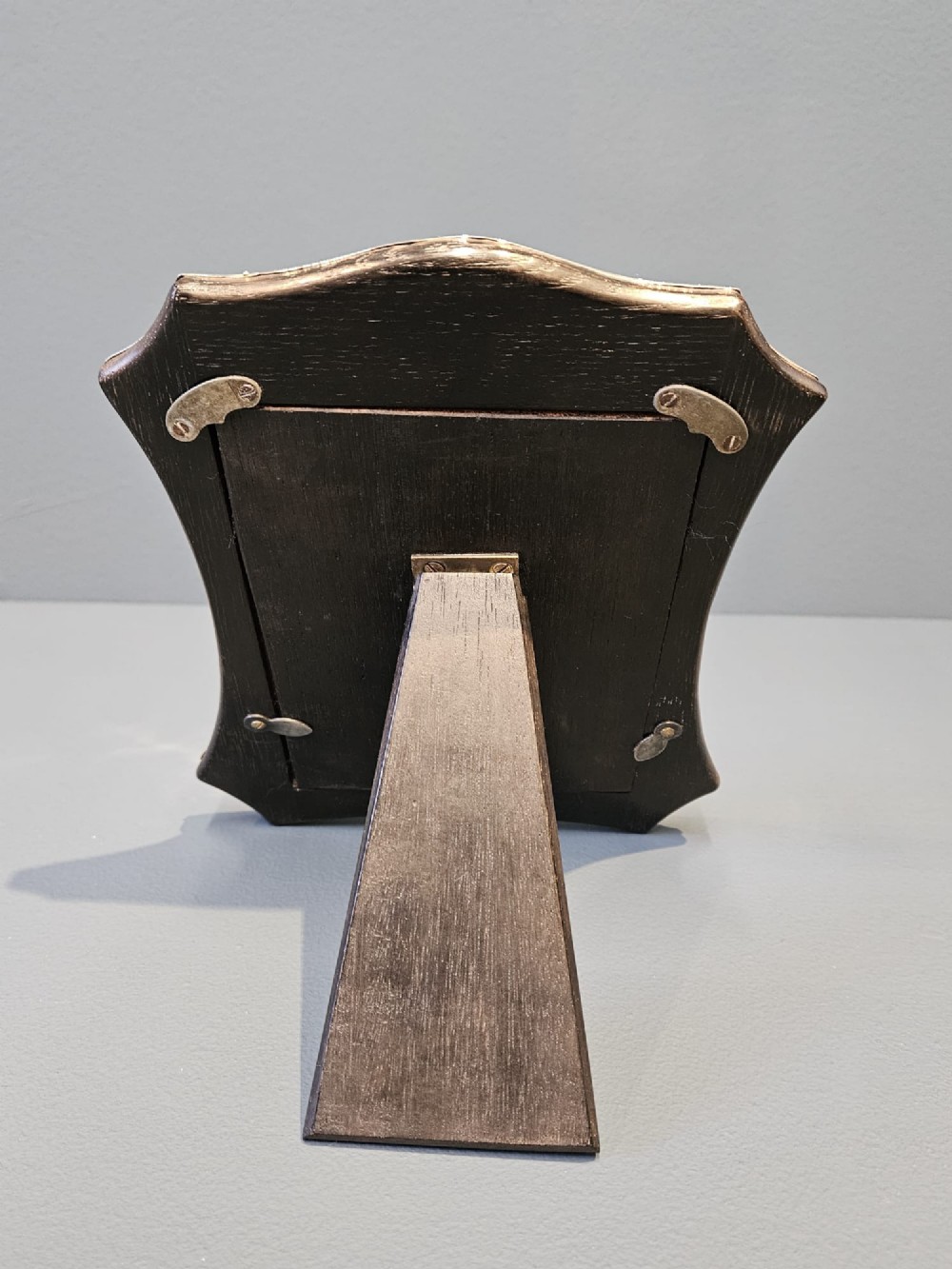 An Edwardian sterling silver photo frame featuring swept concave sides, a shaped crest, polished silver surface, and portrait orientation. View VII