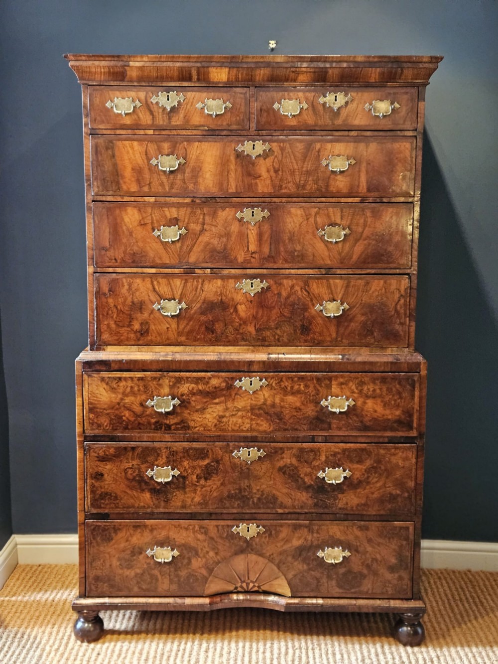 A George I burr walnut chest on chest featuring multiple stacked drawers with brass escutcheons and a dished sunburst motif on the lower drawer.