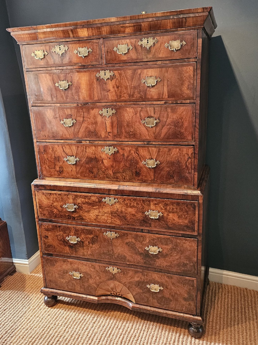 A George I burr walnut chest on chest featuring multiple stacked drawers with brass escutcheons and a dished sunburst motif on the lower drawer. View IV