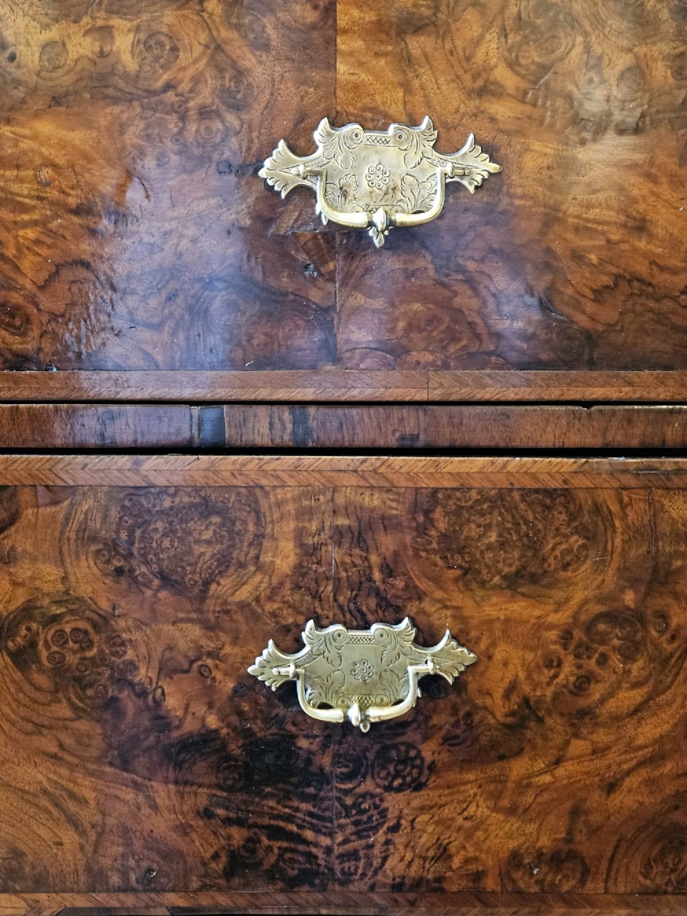 A George I burr walnut chest on chest featuring multiple stacked drawers with brass escutcheons and a dished sunburst motif on the lower drawer. View V