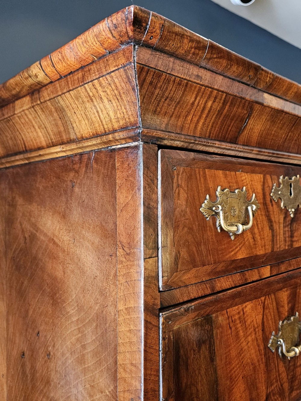 A George I burr walnut chest on chest featuring multiple stacked drawers with brass escutcheons and a dished sunburst motif on the lower drawer. View IX