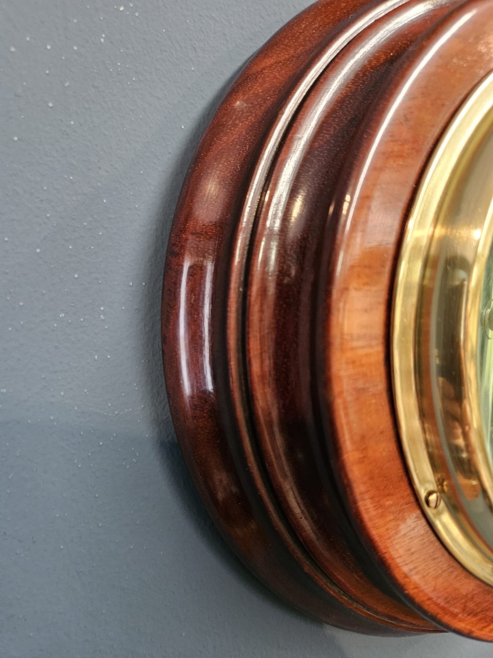 A circular Victorian aneroid barometer set within a polished mahogany surround with an engraved brass dial face and brass bezel. View III