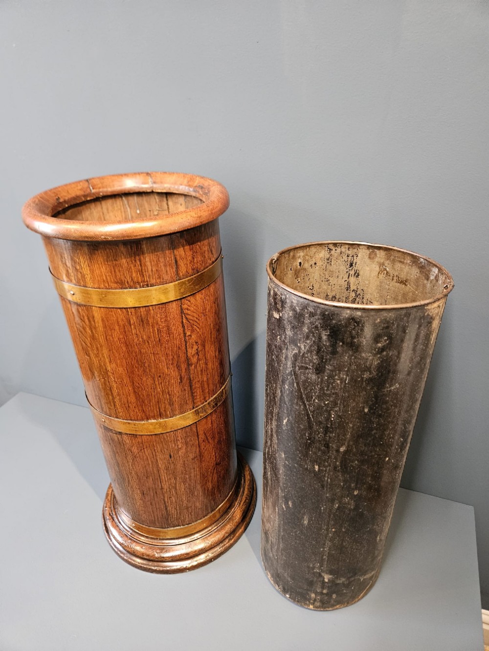 A cylindrical Victorian oak stick stand featuring polished brass binding straps and a moulded circular base. View V