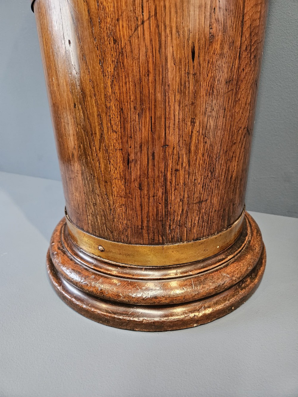 A cylindrical Victorian oak stick stand featuring polished brass binding straps and a moulded circular base. View VI