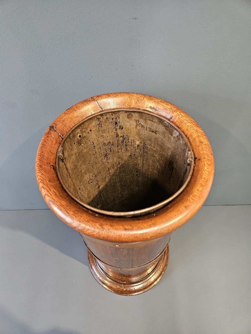 A cylindrical Victorian oak stick stand featuring polished brass binding straps and a moulded circular base. View VII
