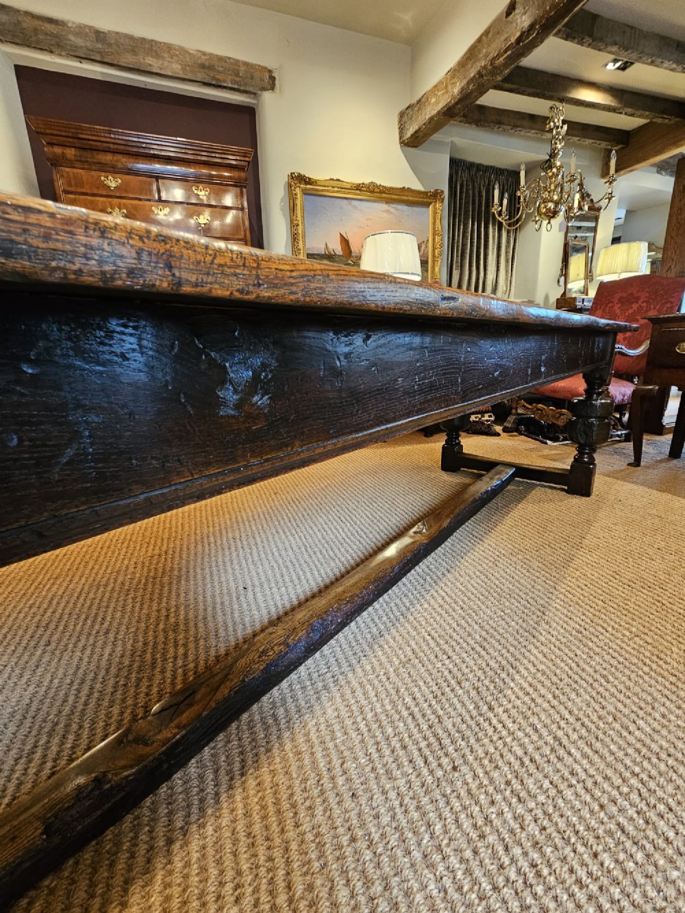 A long George II dark oak refectory dining table featuring a solid plank top, turned legs, and low stretcher rails. View X